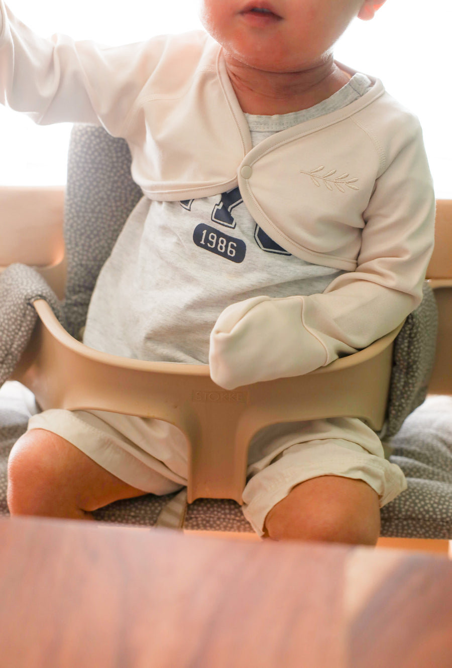 Toddler wearing beige anti-scratch sleeve with mitten cuff covering hand