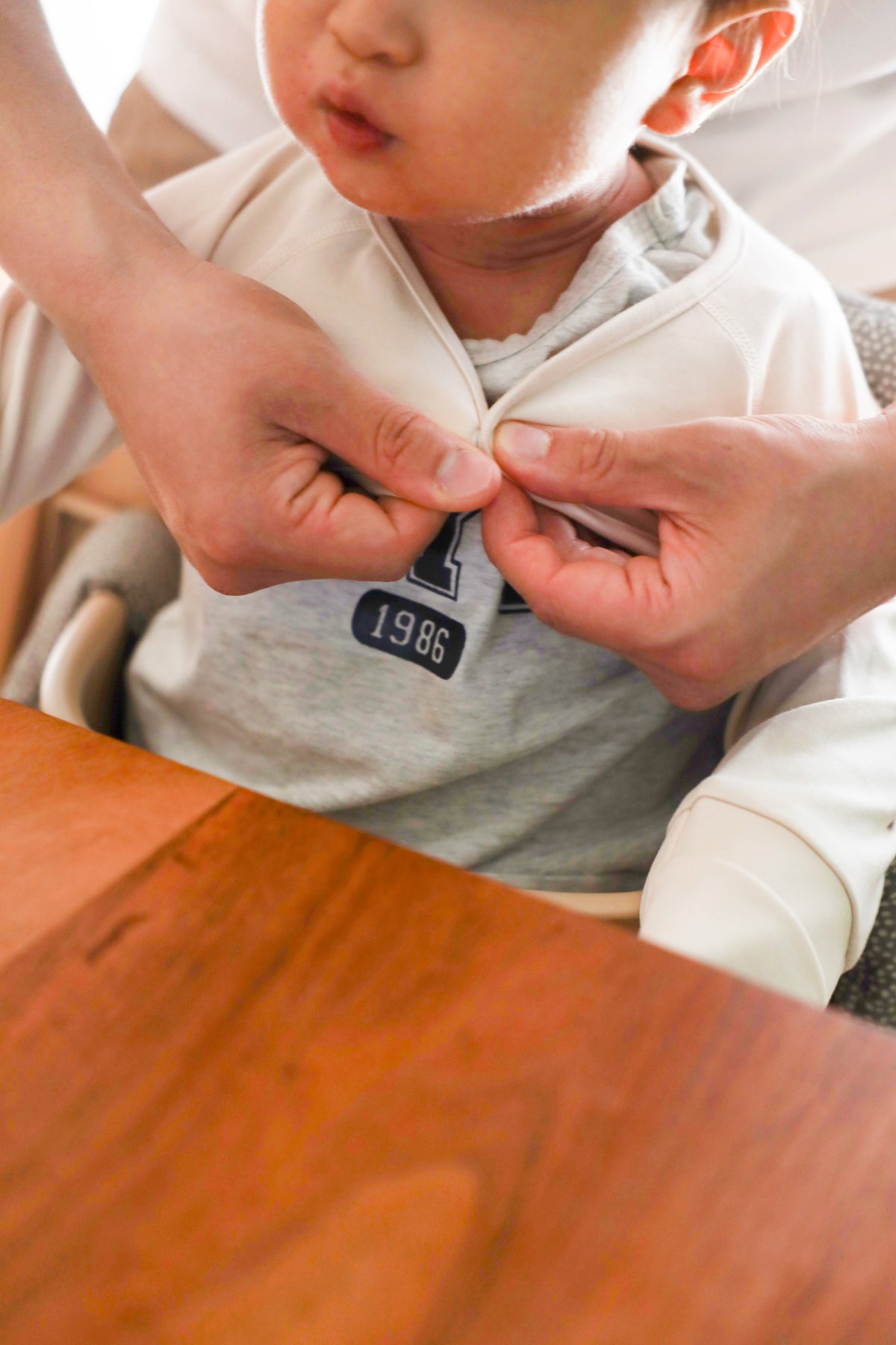 Parent fastening the front snap closure of the beige anti-scratch sleeve