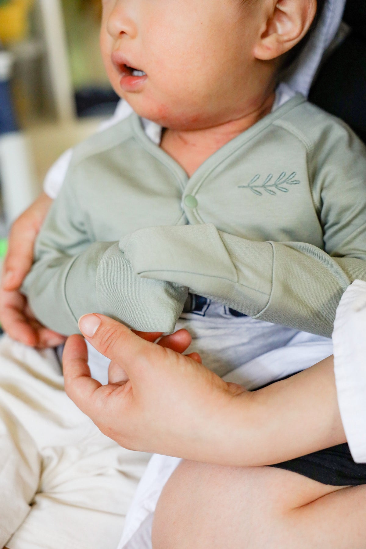 Toddler wearing sage green anti-scratch sleeve with olive branch embroidery